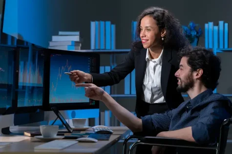 business men and women who are working hard Working late into the night to complete tasks according to set goals The two of them looked at the company's financial graph attentively.