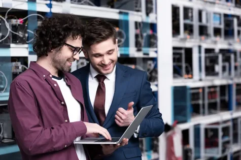 happy young businessman and computer engineer working together at ethereum mining farm